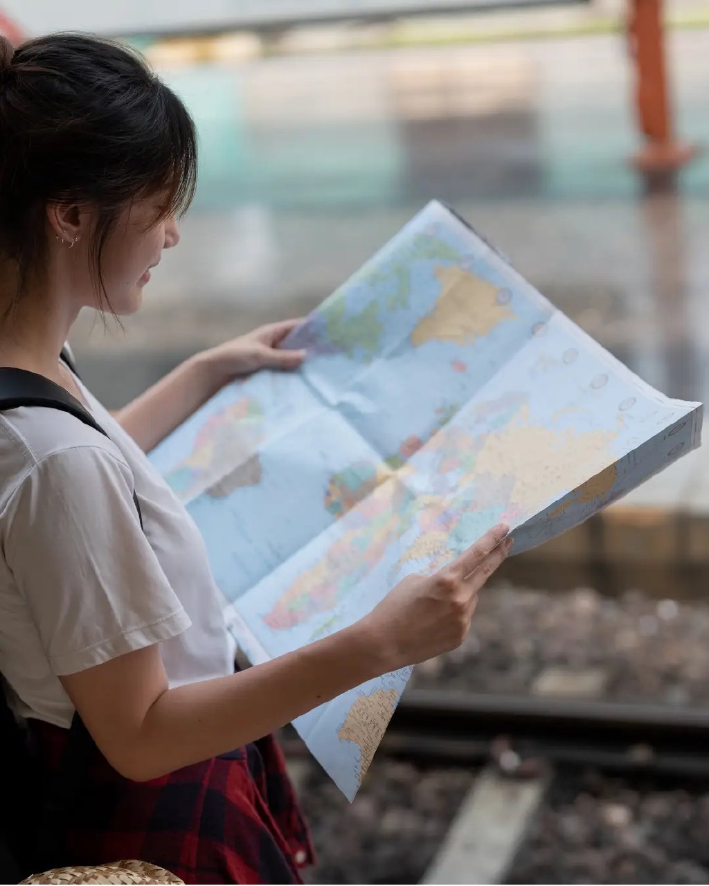 Young woman looking at a map outdoors near train tracks